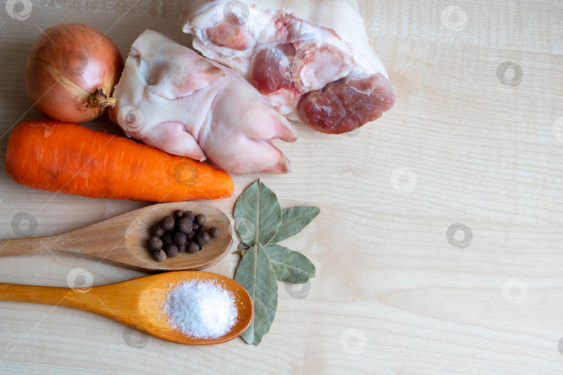 Скачать Сырое свиное мясо и окорочка, морковь и лук, соль и перец выложите на кухонный стол для приготовления желе. место для вашего текста фотосток Ozero