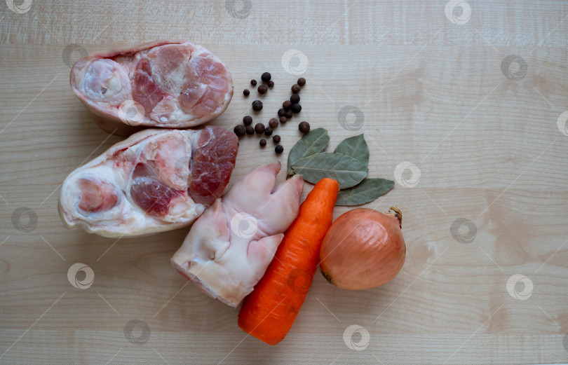 Скачать Сырое свиное мясо и окорочка, морковь и лук на кухонном столе для приготовления желе фотосток Ozero
