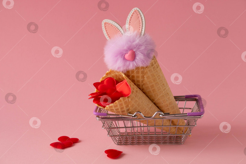 Скачать Абстрактный розовый фон с красными сердечками и пушистым сиреневым кроликом в продуктовой корзине и вафельных рожках. Концепция любви, поздравительная открытка ко Дню святого Валентина и Пасхе. фотосток Ozero