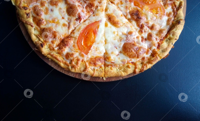 Скачать Половинка вкусной пиццы на черном фоне стола фотосток Ozero