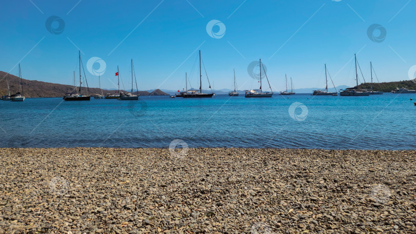 Скачать Галечный пляж, море и яхты с турецкими флагами фотосток Ozero