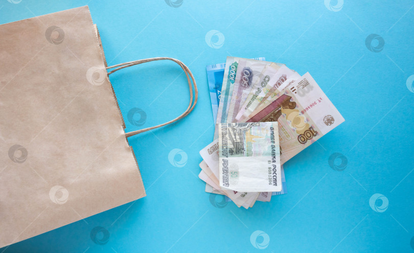 Скачать Пачка российских денег и бумажный пакет на синем фоне. Место для вашего текста фотосток Ozero