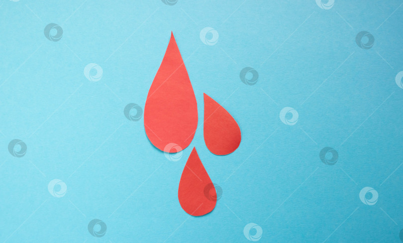 Скачать Концепция Всемирного дня донора крови и борьбы с гемофилией. Капли крови на красной бумаге на синем фоне фотосток Ozero