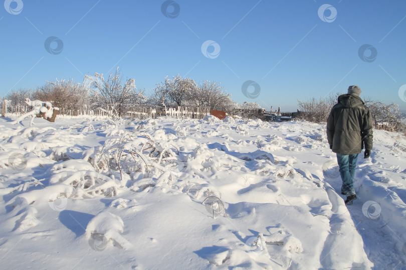 Скачать Мужчина идёт по снегу в деревне. фотосток Ozero