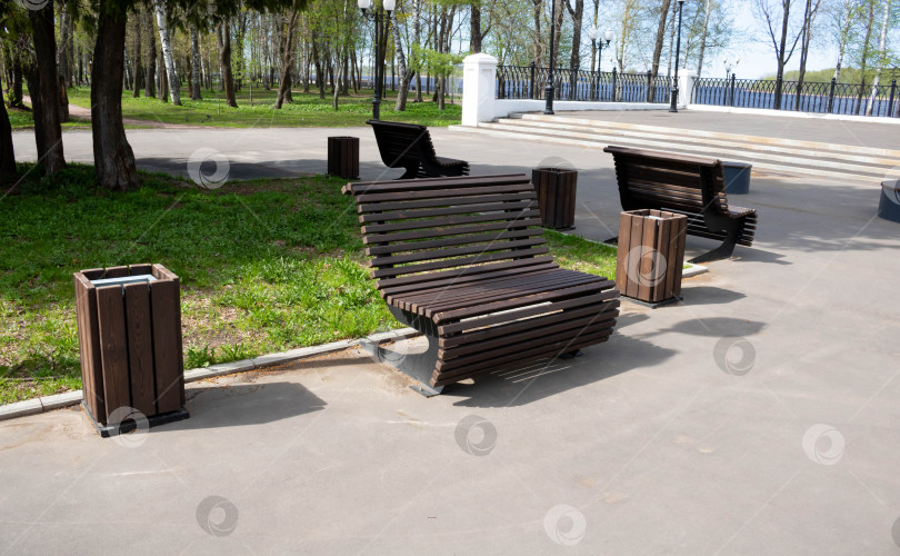 Скачать Деревянная коричневая скамейка в городском парке ярким весенним днем фотосток Ozero