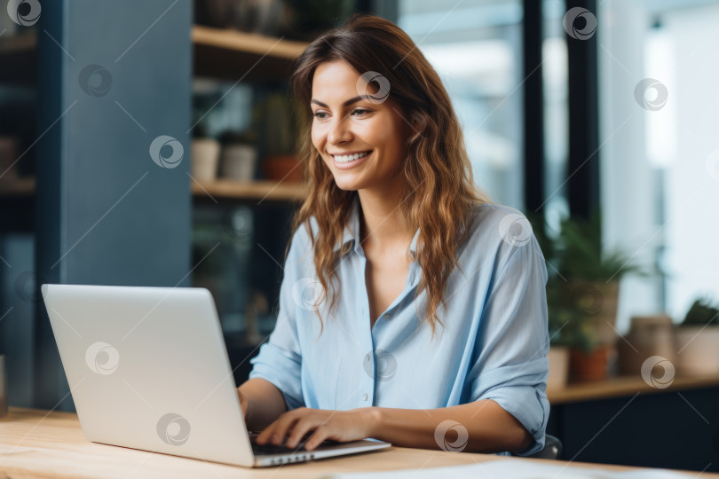 Скачать Красивая женщина в светло-голубой рубашке улыбается и работает на своем ноутбуке. Небольшая глубина резкости, выборочный фокус фотосток Ozero