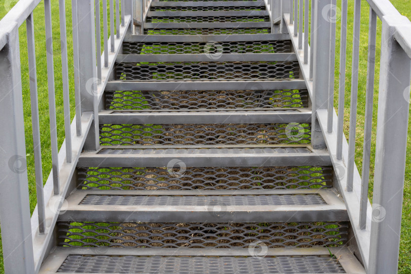 Скачать Серая железная лестница с перилами на фоне зеленой травы фотосток Ozero