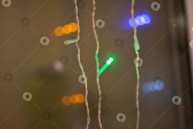 Скачать Праздничная разноцветная гирлянда горит у окна фотосток Ozero
