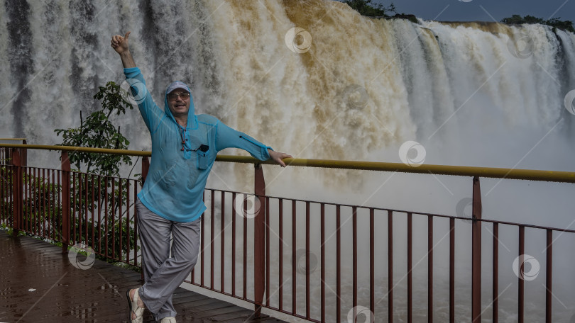Скачать Мужчина стоит на смотровой площадке у водопада фотосток Ozero