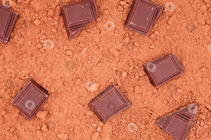 Скачать Кусочки шоколада лежащий на какао фоне. Вид сверху. кусочек шоколада для какао-фона фотосток Ozero