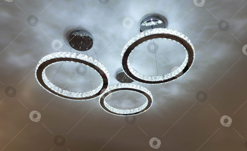 Скачать Красивая светящаяся яркая люстра в форме кругов на потолке фотосток Ozero