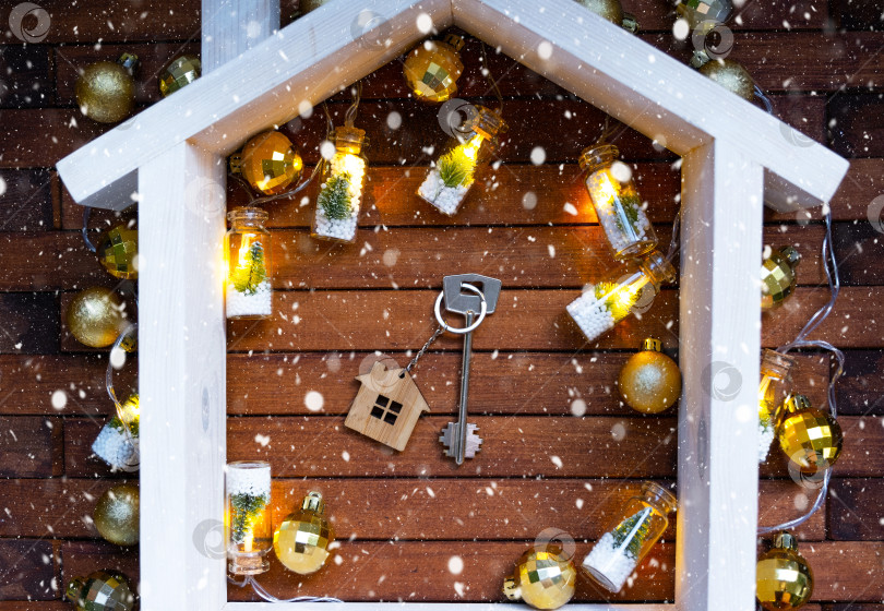 Скачать Ключ от дома с брелком крошечный домик на деревянном фоне с рождественским декором. Подарок на Новый год, Рождество. Строительство, проект, переезд в новый дом, ипотека, аренда и покупка недвижимости фотосток Ozero