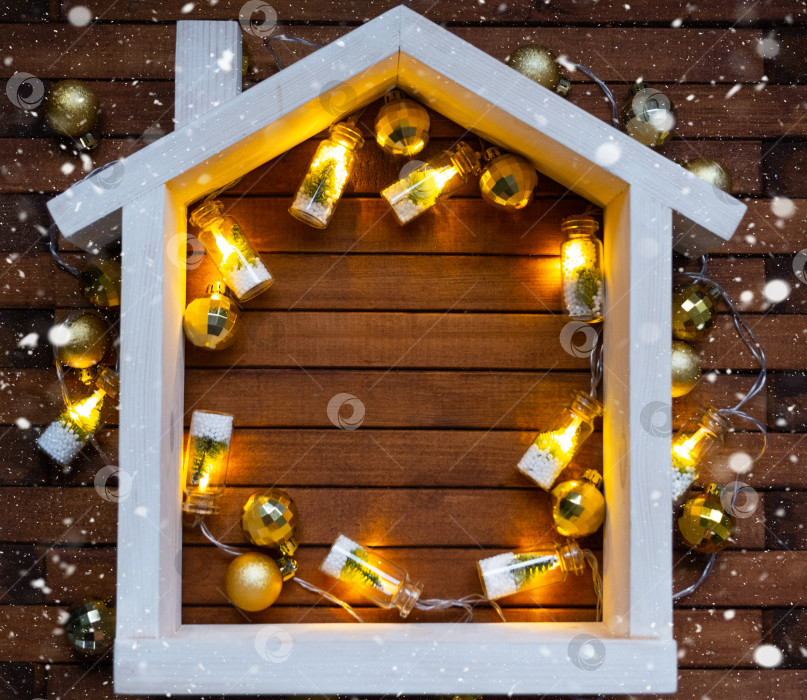 Скачать Крошечный каркасный домик на деревянном фоне с рождественским декором, макетом и копировальным пространством. Подарок на Новый год, Рождество. Строительство, проект, переезд в новый дом, ипотека, аренда и покупка недвижимости фотосток Ozero