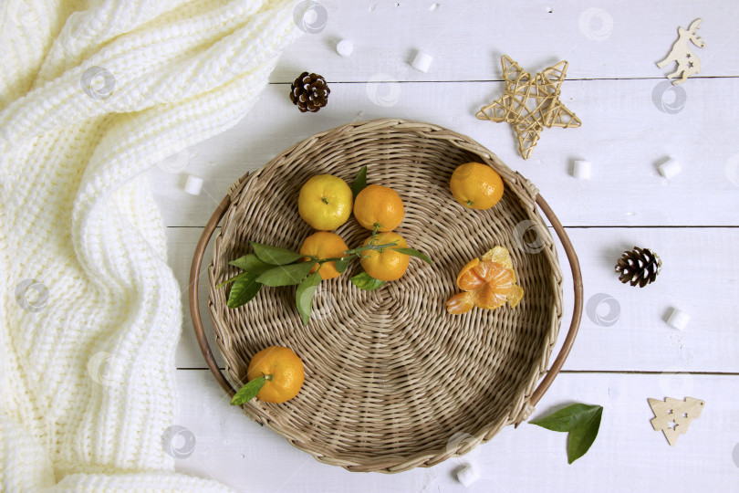 Скачать Круглый плетеный поднос с мандаринами на деревянном столе фотосток Ozero