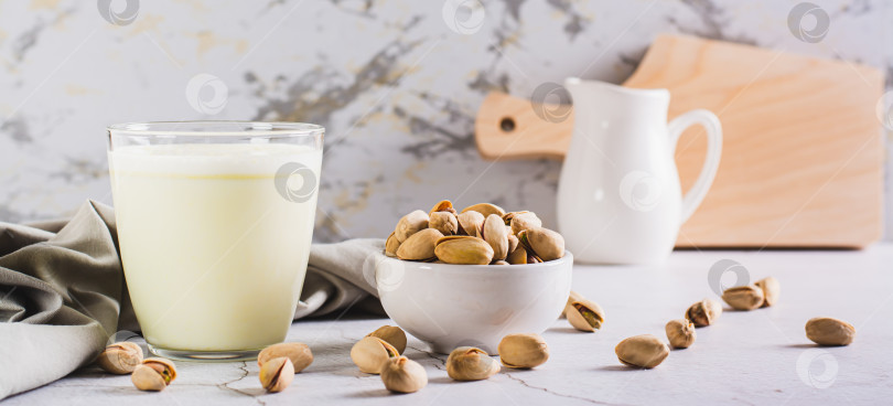 Скачать Фисташковое молоко без лактозы в стакане и орехи на столе веб-баннер фотосток Ozero