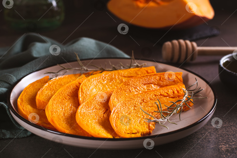 Скачать Кусочки домашней запеченной тыквы с розмарином на тарелке на столе фотосток Ozero