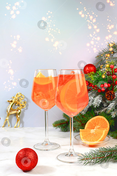 Скачать Рождественский алкогольный коктейль Aperol spritz в бокалах на праздничном фоне с еловыми ветками и украшениями, концепция бара и канун нового года, алкогольные напитки на вечеринке, фотосток Ozero