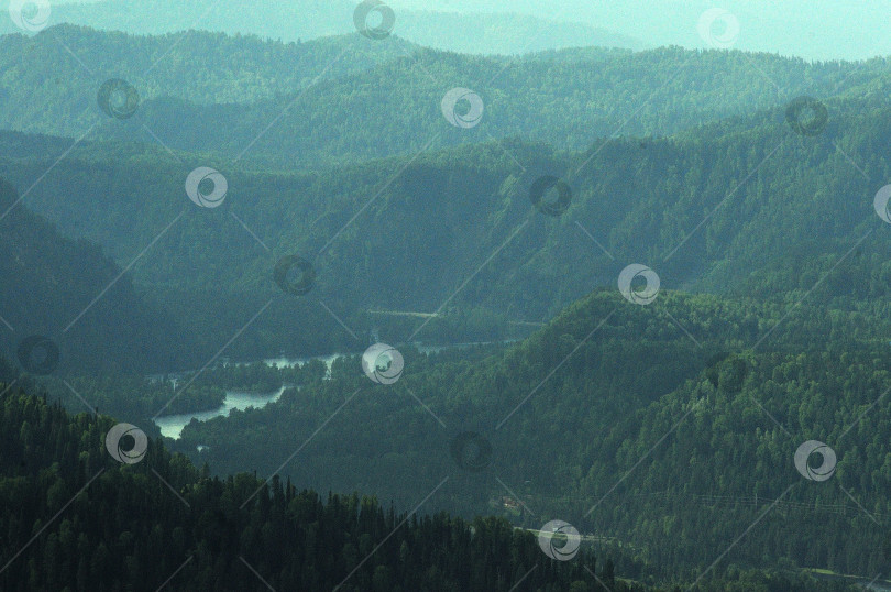 Скачать Взгляните на склоны и вершины высоких гор, покрытых хвойными лесами, и красивую реку, текущую по долине внизу. фотосток Ozero