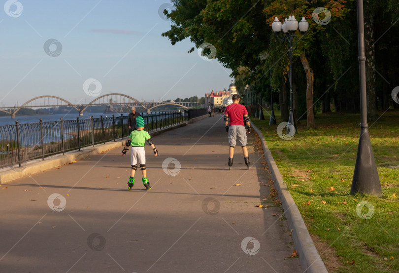 Скачать Отец учит сына кататься на роликовых коньках в парке фотосток Ozero