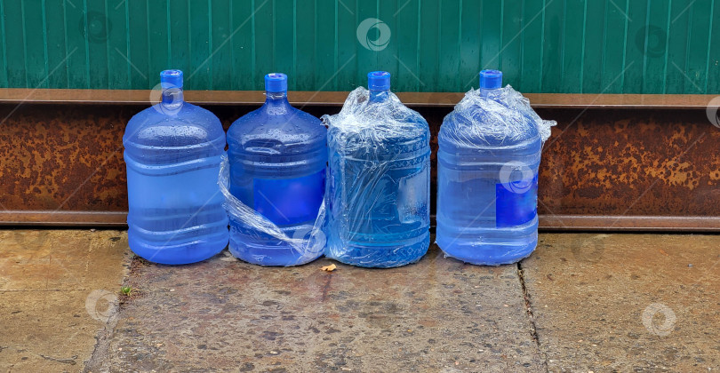 Скачать У забора стоят синие большие пластиковые бутылки с водой фотосток Ozero
