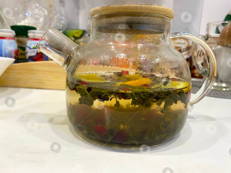 Скачать Стеклянный чайник с травяным чаем с лимоном и клюквой фотосток Ozero