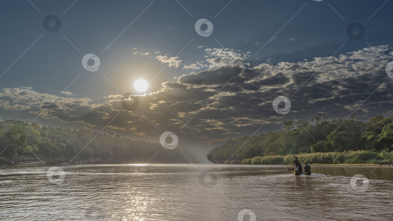 Скачать Каноэ с туристами плывет по спокойной красно-коричневой реке. фотосток Ozero