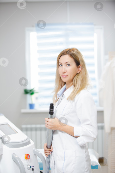 Скачать Красивая женщина-врач стоит в современно оборудованном салоне красоты, держа в руке инструмент для карбонового пилинга фотосток Ozero