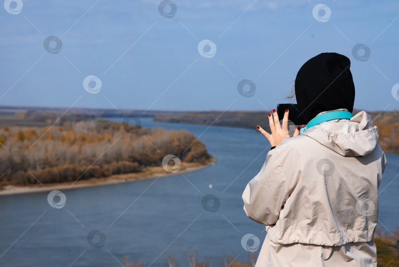 Скачать Женщина фотографирует море. Вид сзади. фотосток Ozero