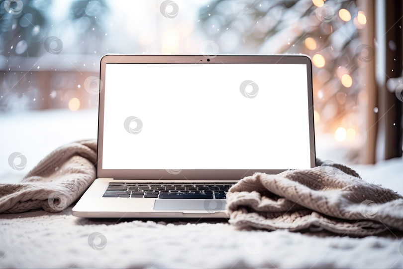 Скачать Макет ноутбука с белым экраном зимой, на улице в снегу, укрывшись уютным одеялом во время снегопада. Сезонная удаленная работа, Интернет, шоппинг, Рождество и Новый год. Искусственный интеллект сгенерирован фотосток Ozero