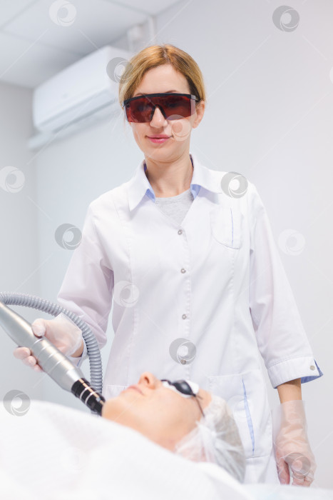 Скачать снимок лица молодой девушки в защитных очках во время процедуры карбонового пилинга в салоне красоты фотосток Ozero