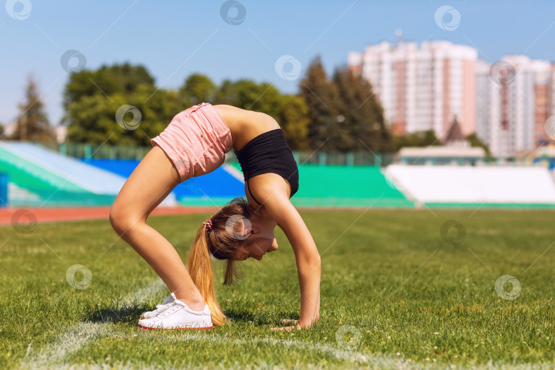 Скачать Девочка-подросток выполняет упражнение по подтягиванию на стадионе теплым летним днем фотосток Ozero