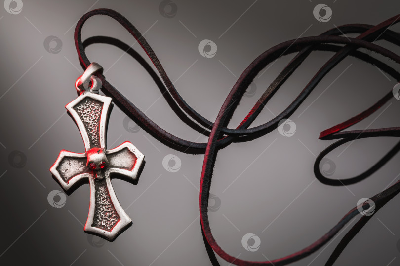 Скачать Металлический крест с кожаным шнурком на темном градиентном фоне фотосток Ozero
