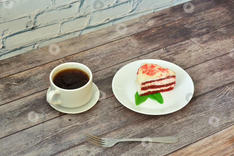 Скачать Чашка горячего кофе на блюдце и тарелка с кусочком чизкейка "красный бархат" с листьями мяты на деревянном столе. фотосток Ozero