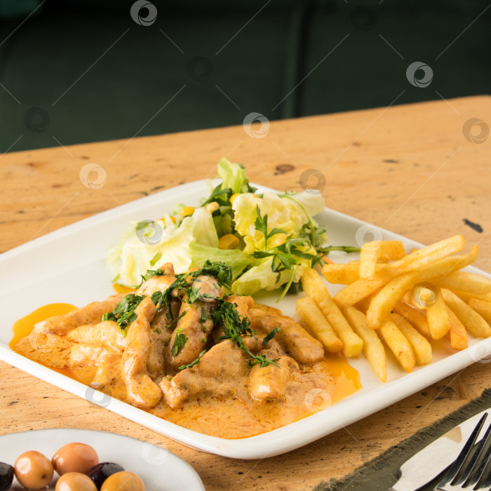 Скачать Крупным планом блюдо с курицей, картофелем фри, салатом и оливками на столе фотосток Ozero