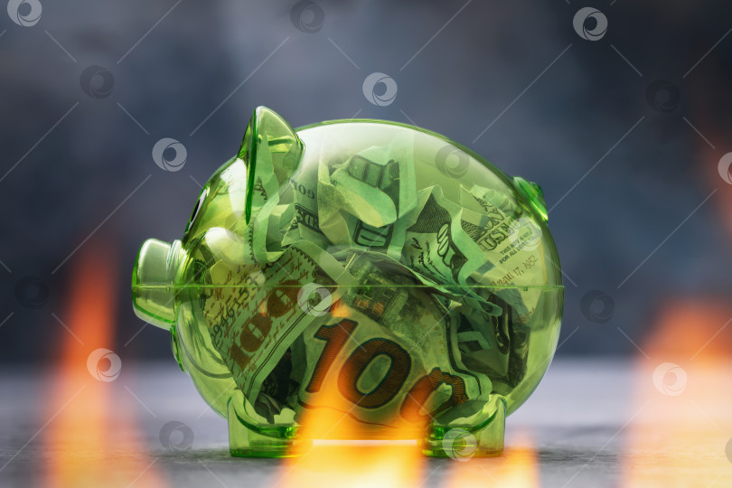 Скачать Доллары в прозрачной копилке, окруженные огнем, концепция инфляции и сжигания депозитов фотосток Ozero