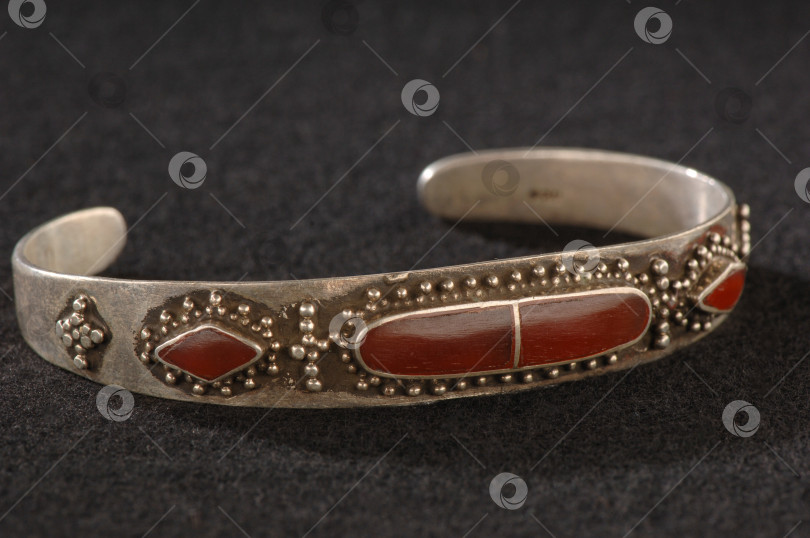 Скачать Старинный элегантный браслет с гравировкой и драгоценными красными камнями, выделенными на черном фоне фотосток Ozero