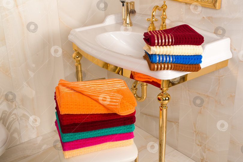Скачать Сложенные разноцветные бамбуковые полотенца в красивом винтажном золотистом интерьере ванной комнаты фотосток Ozero