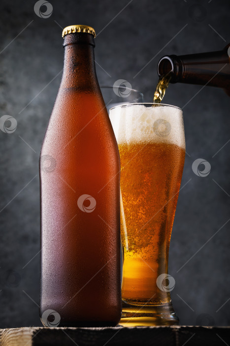 Скачать Бутылка светлого пива и полный стакан напитка на деревянном столе. Алкогольный натюрморт крупным планом фотосток Ozero