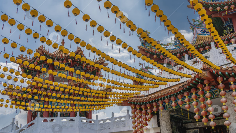 Скачать Ряды ярко-желтых и красных китайских фонариков развешаны на фоне голубого неба фотосток Ozero