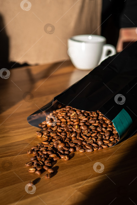 Скачать Кофейные зерна высыпались из пакета на деревянный фон фотосток Ozero