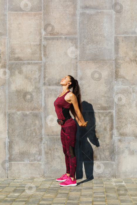 Скачать Молодая женщина спортивного телосложения занимается зарядкой у стены на свежем воздухе летним солнечным утром фотосток Ozero
