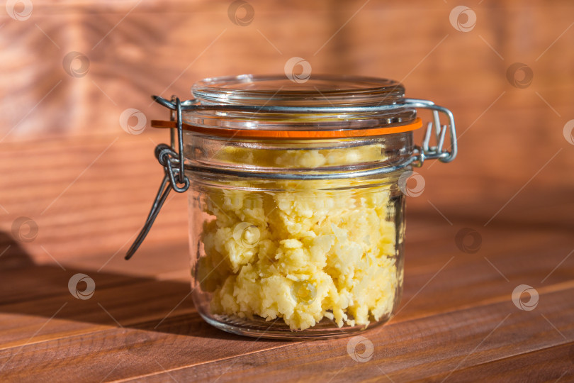 Скачать Сырный паштет с чесноком в прозрачной банке на деревянном столе в sunny kitchen. фотосток Ozero