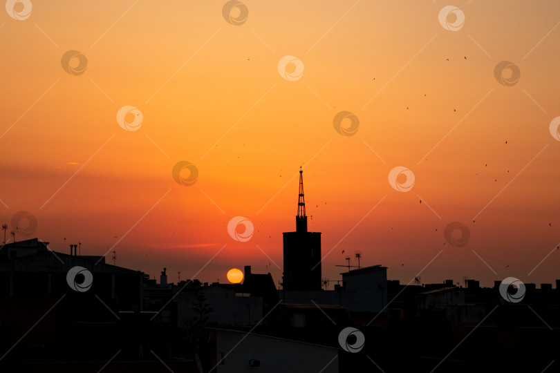 Скачать Оранжевый летний восход солнца, вид с крыши на старую церковную башню над городом. фотосток Ozero