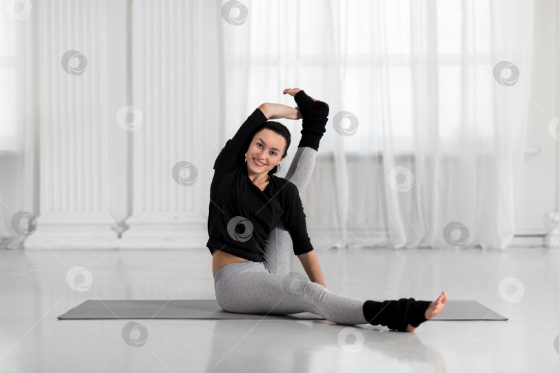 Скачать Молодая азиатка практикует йогу, сидя с поднятой ногой в позе компаса. Тренировка в студии белой йоги. фотосток Ozero