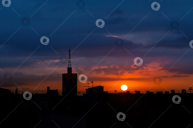Скачать Солнце встает над городом, вид с крыши на старую церковную башню. фотосток Ozero