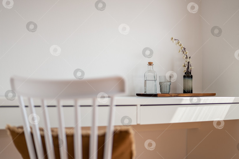 Скачать Размытая спинка деревянного стула крупным планом на фоне стола с вазой цветов, стаканом и бутылкой воды в гостиничном номере. Концепция отдыха в пятизвездочном отеле для VIP-персон. Copyspace фотосток Ozero