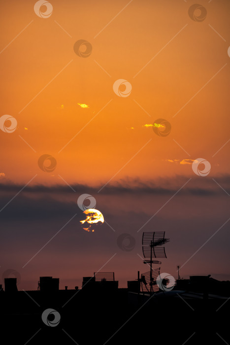 Скачать Солнце появляется из-за облаков над городом, вид сверху на крышу. фотосток Ozero
