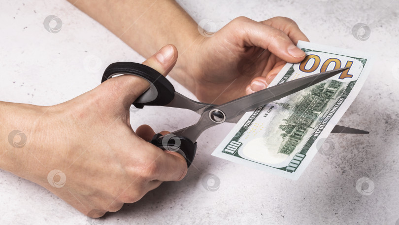 Скачать Мужчина режет доллары ножницами. Концепция на тему девальвации денег в стране фотосток Ozero