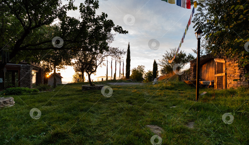 Скачать Восход солнца в деревне, вид на лужайку, окруженную домами фотосток Ozero