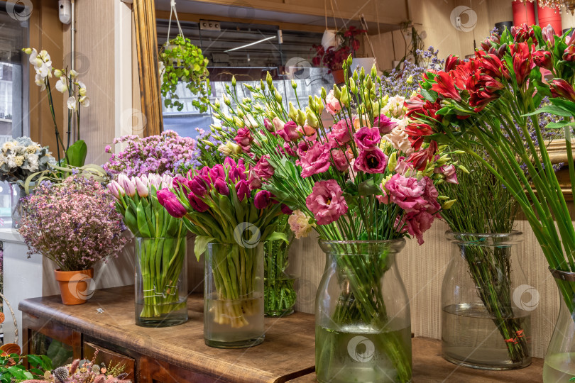 Скачать Ассортимент красивых цветов в магазине для продажи, расставленных в вазах в цветочном магазине. Тюльпаны, розы и лимониум фотосток Ozero